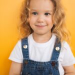 a little girl holding a tomato in her hands